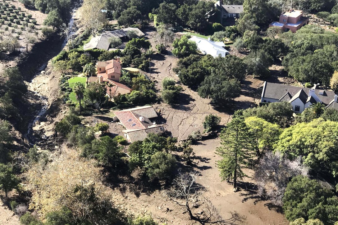 An aerial view taken from a HH-60G Pave Hawk rescue helicopter shows a pararescueman searching around houses for stranded residents.