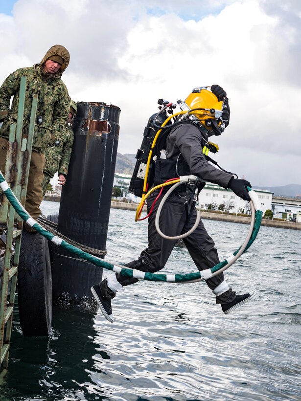 Petty Officer 2nd Class Mitchell Apgar enters the water to participate in an underwater pile removal operation.