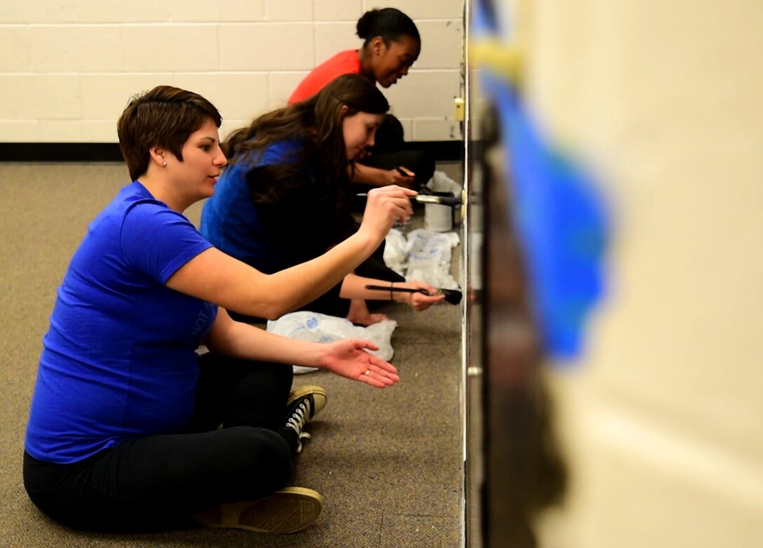 (From left to right) Staff Sgt. Christina Powell, the unit training manager assigned to the 28th Security Forces Squadron, along with Airman First Class Savannah Dudley and Senior Airman Tkeyah Charley, response force members assigned to the 28th SFS, paint a wall with chalkboard paint inside the new Little Defenders Den in the Base Defense Operations Center on Ellsworth Air Force Base, S.D., Dec. 10, 2017. The 28th SFS is building this family room to provide a safe and comfortable place for nursing mothers and serve as a location to bring children during squadron events or possible re-calls. (U.S. Air Force photo by Senior Airman Denise M. Jenson)