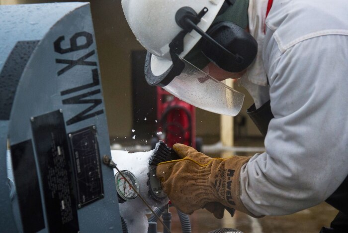 And airman chips ice from a 50-gallon liquid oxygen cart.