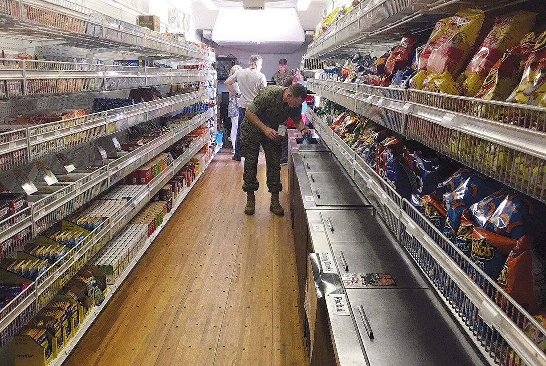 A Marine shops in the Mobile Tactical Field Exchange. This 9 foot vehicle has two doors with detachable stairs, a rear motorized lading dock and runs on 12 kilowatts of electricity. The interior walls are lined with shelved baskets, three reach in coolers, cash register and heating and cooling air conditioning system. Cpl. Tyler Duffner, clubs assistant manager at Marine Barracks 8th and I mans the register.