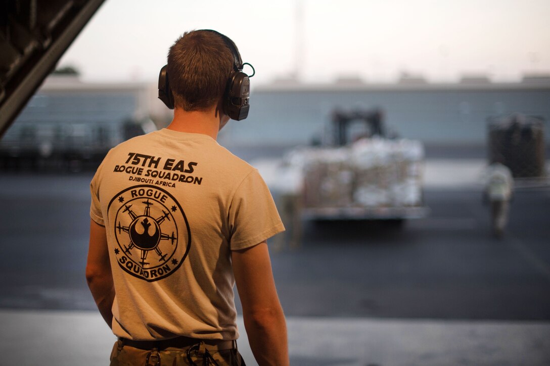 An airman watches as cargo is being uploaded onto a C-130J Super Hercules.