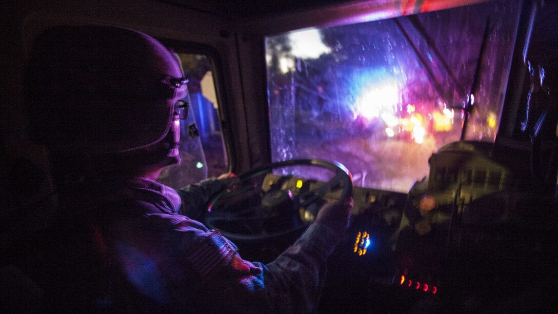 A soldiers drives a tactical vehicle through an area closed off due to a storm-driven mudslide