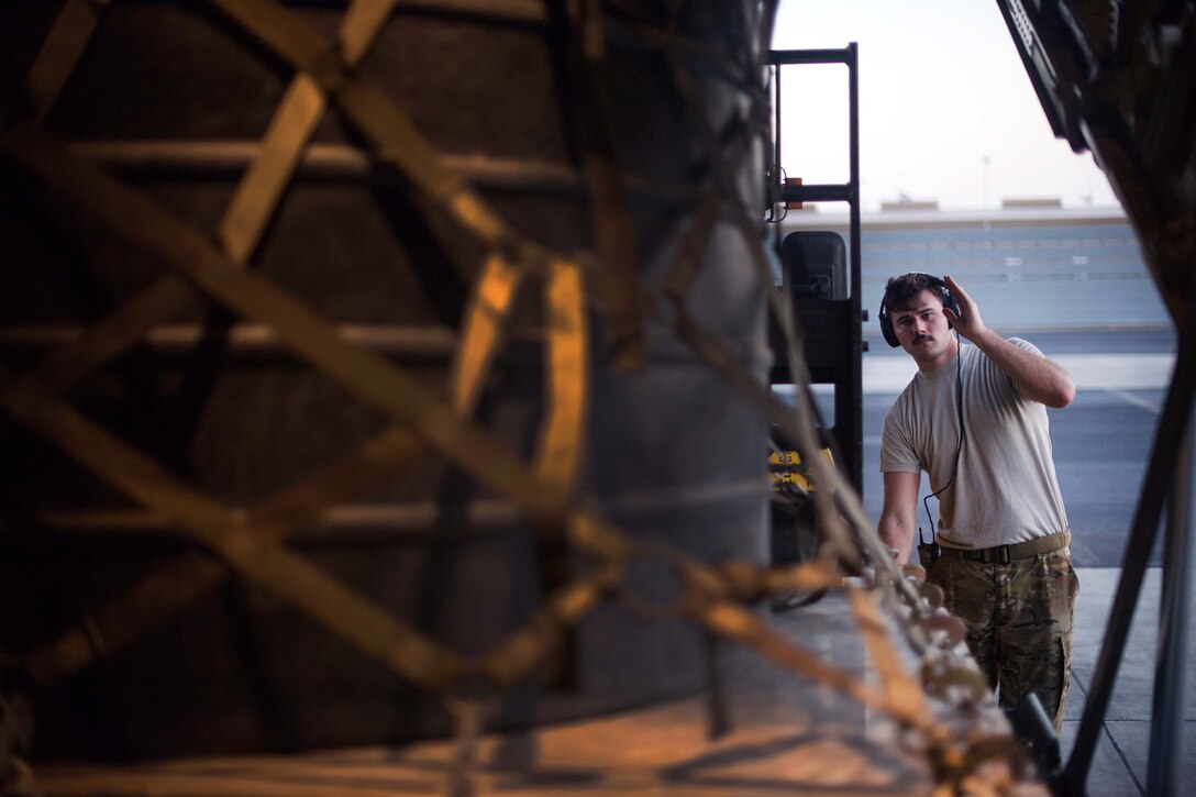An airman directs a forklift operator loading cargo onto a C-130J Super Hercules.