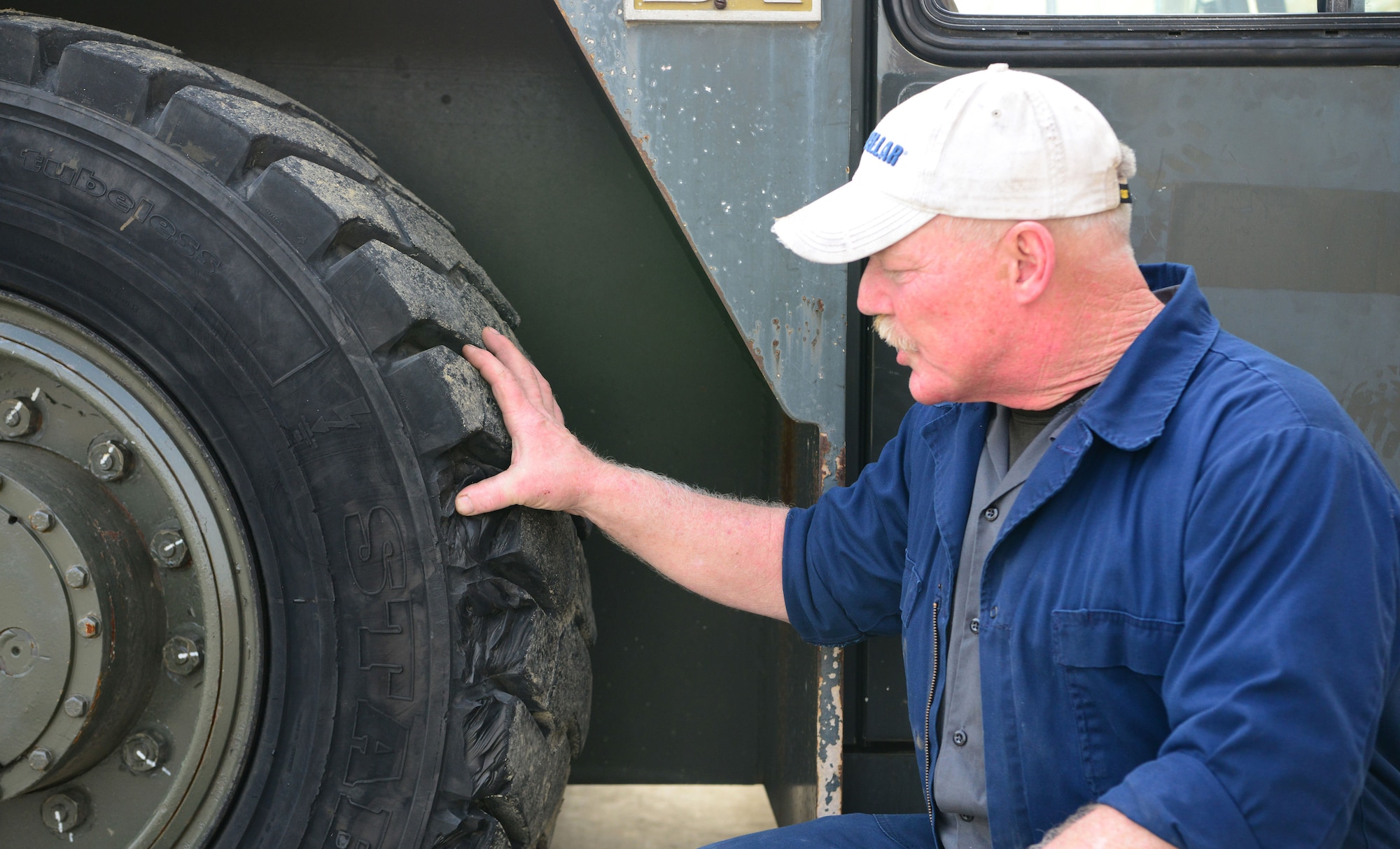 Darryl Crady, 9th Support Division heavy mobile equipment mechanic, inspects a damaged tire