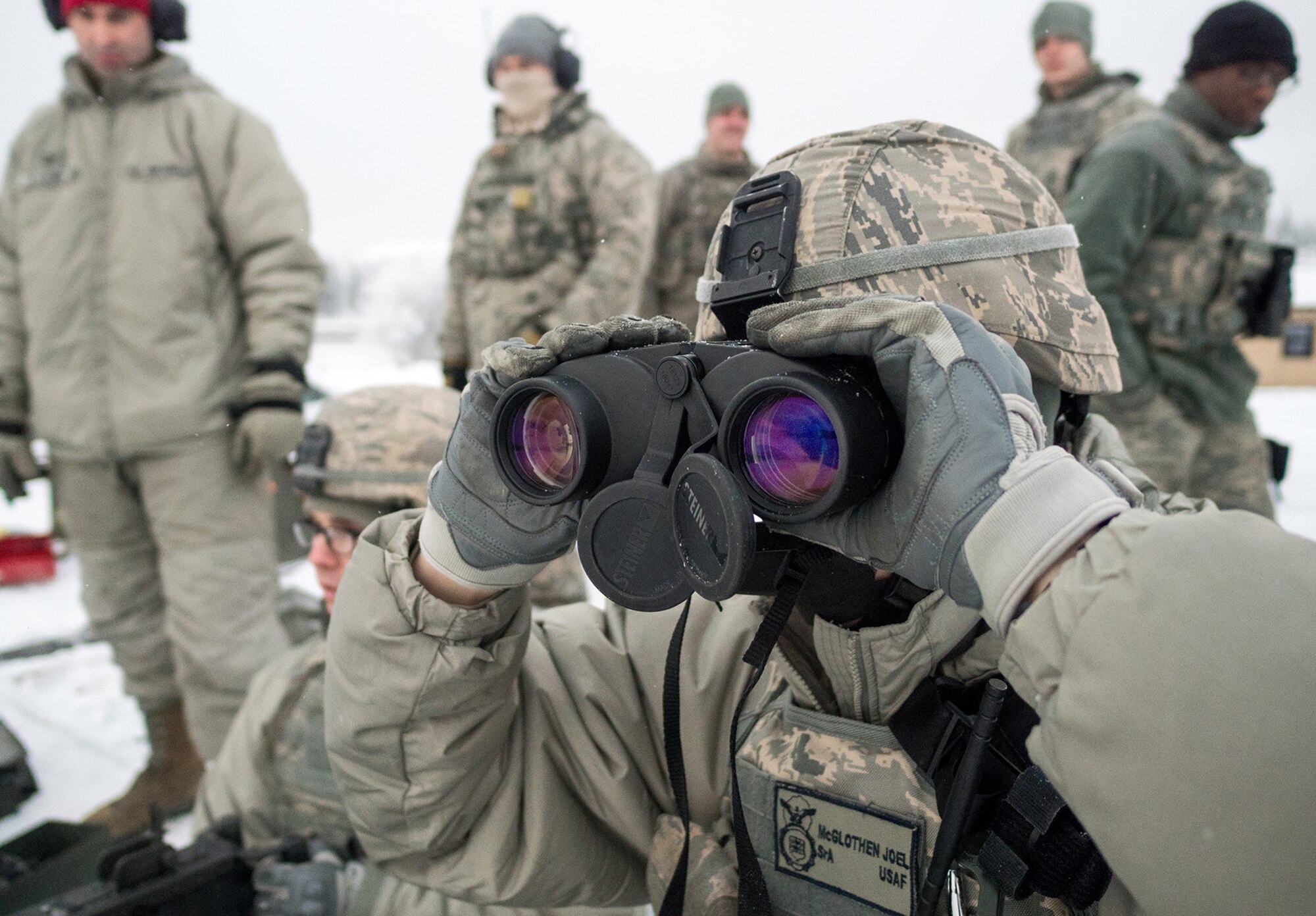 Senior Airman Joel McGlothen, a native of Battle Creek, Mich., uses binoculars to spot targets for Airmen assigned to the 673d Security Forces Squadron conducting an M249 Squad Automatic Weapon, and M2 .50 Caliber machine gun qualification range on Joint Base Elmendorf-Richardson, Alaska, Jan. 10, 2018. Security Forces Airmen perform extensive training in law enforcement as well as combat tactics to protect U.S. Military bases and assets both stateside and overseas.