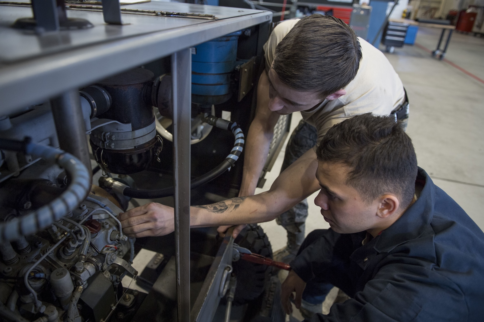 Airman 1st Class Cody Noel, 374th Maintenance Squadron aerospace ground equipment technician, teaches a fellow AGE Airman about how to properly fix a piece of equipment, Jan. 10, 2018, at Yokota Air Base, Japan.