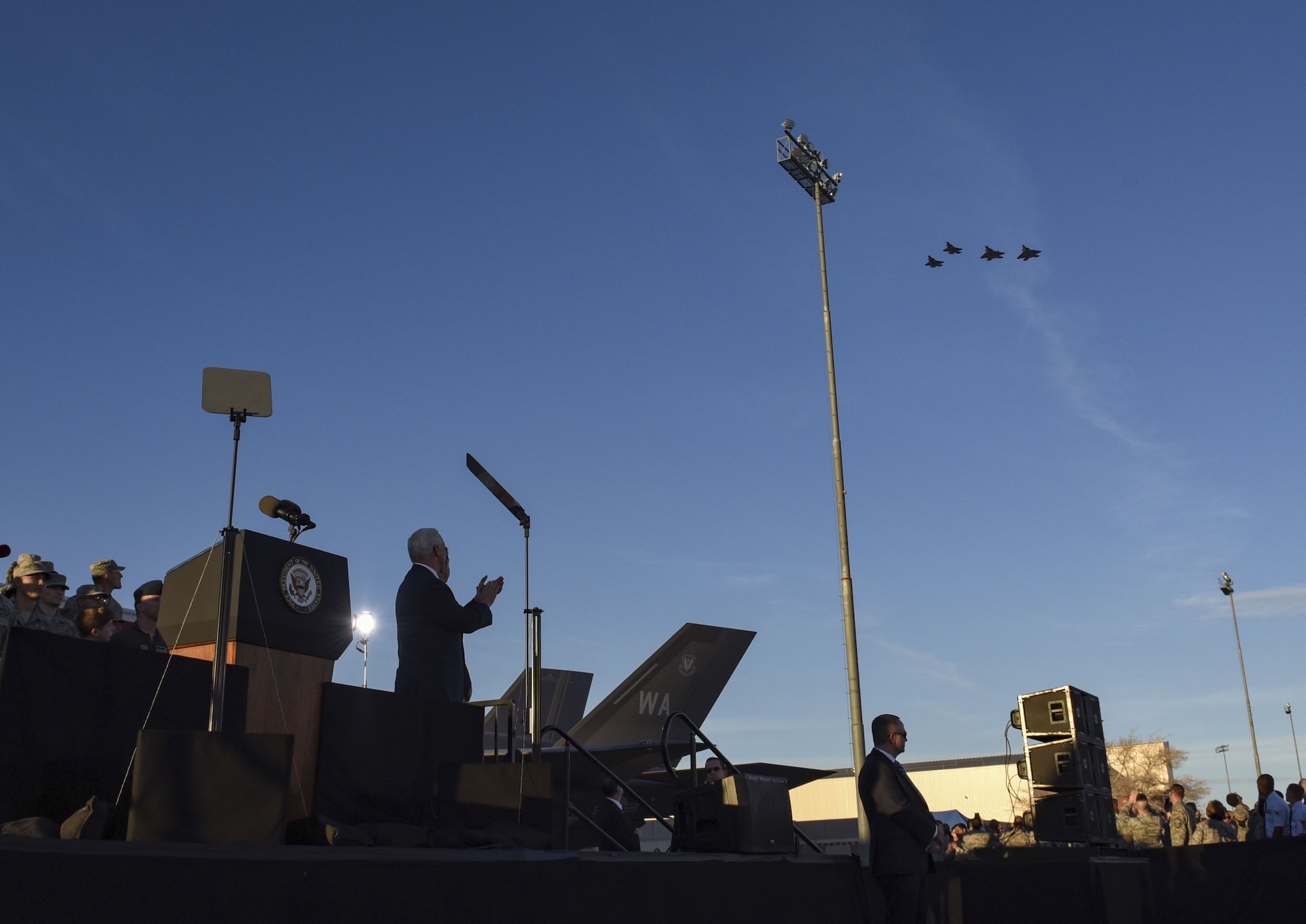 Vice President Mike Pence applauds as two F-35 Lightning II fighter jets, assigned to the 6th Weapons Squadron, and two F-22 Raptor fighter jets, assigned to the 433rd WPS, thunder overhead during his visit at Nellis Air Force Base, Nevada, Jan. 11, 2018. Following the fifth-generation aircraft flyover, Pence turned toward his audience to express his gratitude for a vast history of air superiority. (U.S. Air Force photo by Airman 1st Class Andrew Sarver)