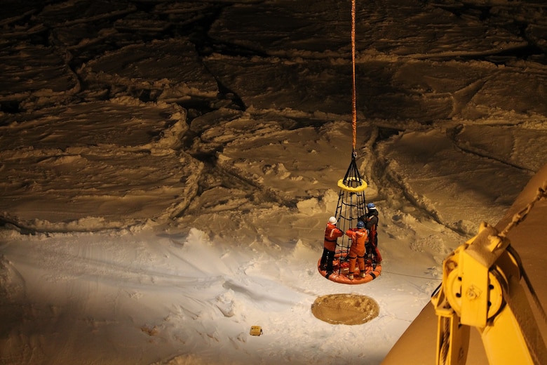 Researchers are lifted from the sea ice to the icebreaker Nathaniel B. Palmer after placing a buoy that measures waves traveling through ice in the marginal ice zone.