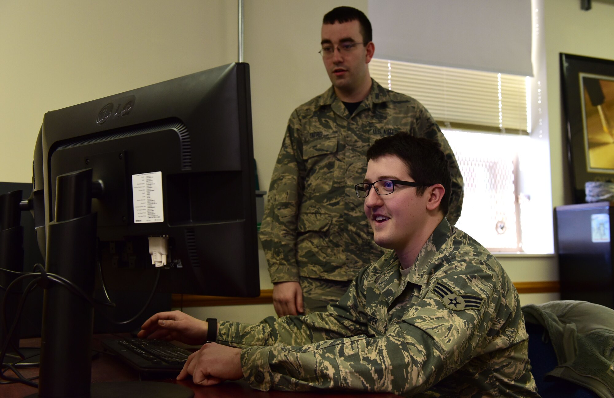 Senior Airman Erik Tatro, left, a programmer with the 595th Strategic Communications Squadron (SCS), and Senior Airman Gregory Salopek, also a programmer with the 595th SCS, sit at a computer in the 595th SCS offices at Offutt Air Force Base, Nebraska, January 12, 2018. Both Airmen participated in a DOD-Silicon Valley partnership in San Francisco in 2017, helping to create a program that would increase the efficiency of the aerial refueling scheduling process.