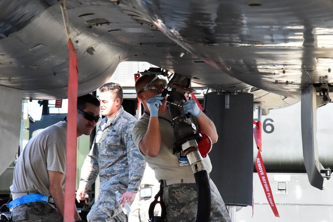 Air Force Staff Sgt. Jason Crandall, right, attaches a fuel nozzle to an F-15C Eagle fighter aircraft.