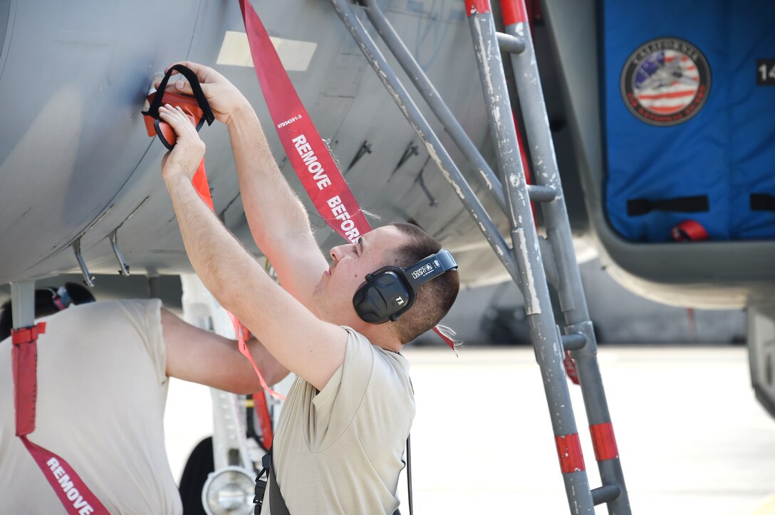 Senior Airman Jamie Mabry-Rairigh replaces a pitot tube cover after post-flight checks on an F-15C Eagle fighter aircraft.