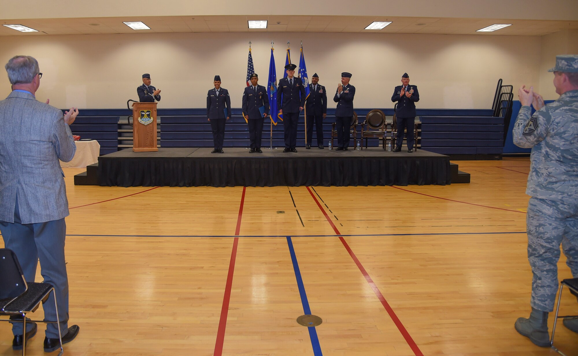 Airmen 1st Class Sharen Vargas-Rodriguez, 460th Medical Operations Squadron medical technician, Jason Dennis , 460th Security Forces Squadron restricted area entry controller, and Christopher Clark, 566th Intelligence Squadron intelligence operator, are applauded for their newest achievement of receiving Senior Airman Below-the-Zone Jan. 12, 2018, at the 460th Space Wing Change of Command ceremony on Buckley Air Force Base, Colorado. (U.S. Air Force photo by Airman 1st Class Holden S. Faul)