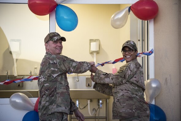 Brig. Gen. Kyle Robinson, 332d Air Expeditionary Wing commander, cuts a ceremonial ribbon with Lt. Col. Lydia Bradley-Tyler, 332d Expeditionary Force Support Squadron commander to re-open the new “Red Tail” dining facility January 11, 2018 in Southwest Asia. The dining facility had been closed for several months due to renovations. (U.S. Air Force photo by Staff Sgt. Joshua Kleinholz)
