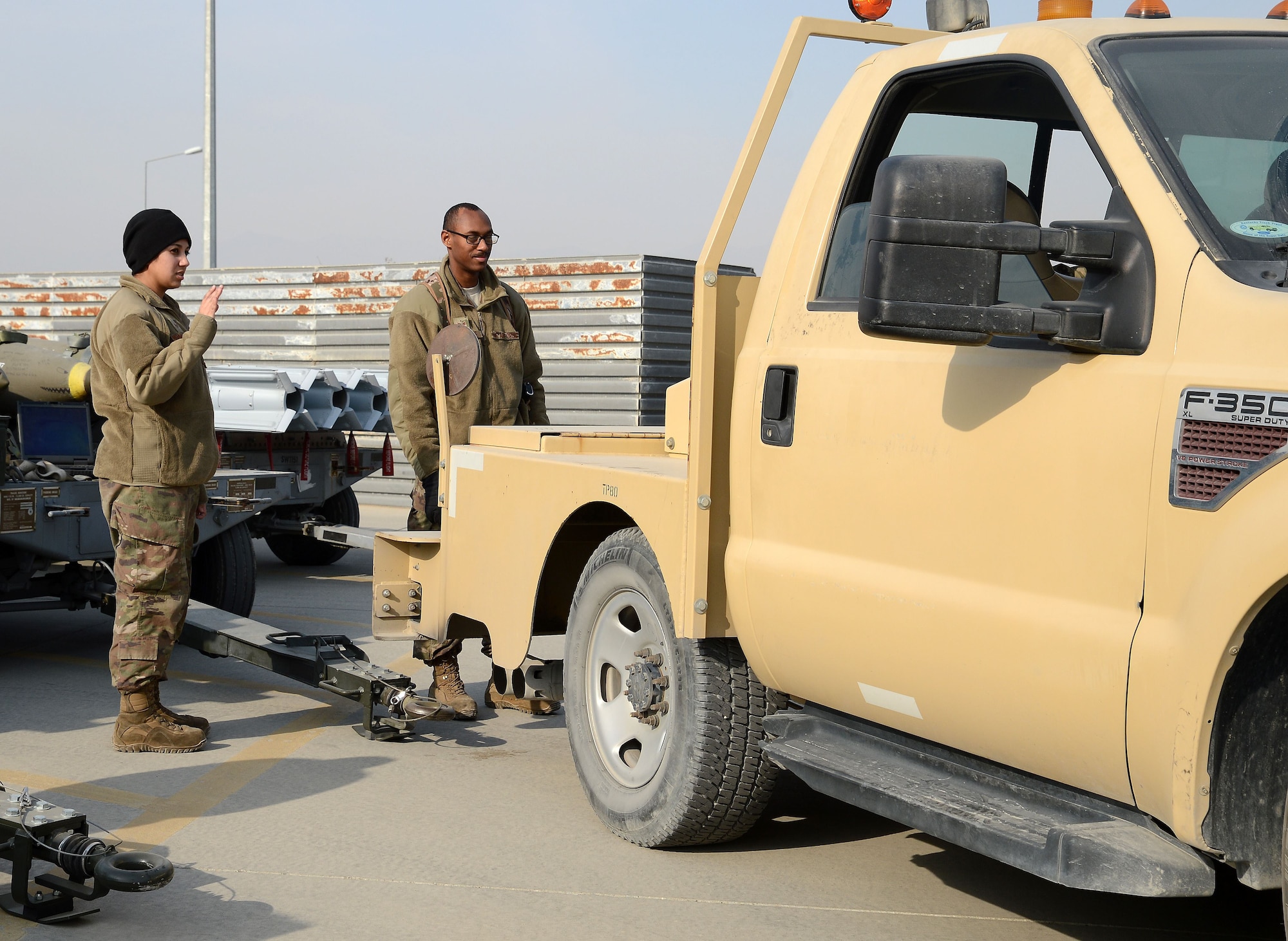 Senior Airman Alyssa Montelongo (left), 455th Expeditionary Maintenance Squadron ammo line delivery crew chief, spots a truck before hooking up a trailer Jan. 8, 2018 at Bagram Airfield, Afghanistan.