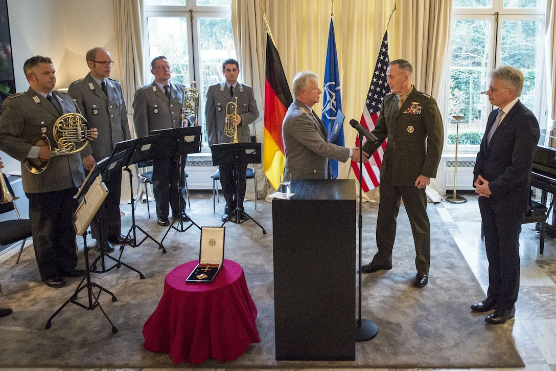 The chairman of the Joint Chiefs of Staff receives a German medal from his counterpart in Brussels.