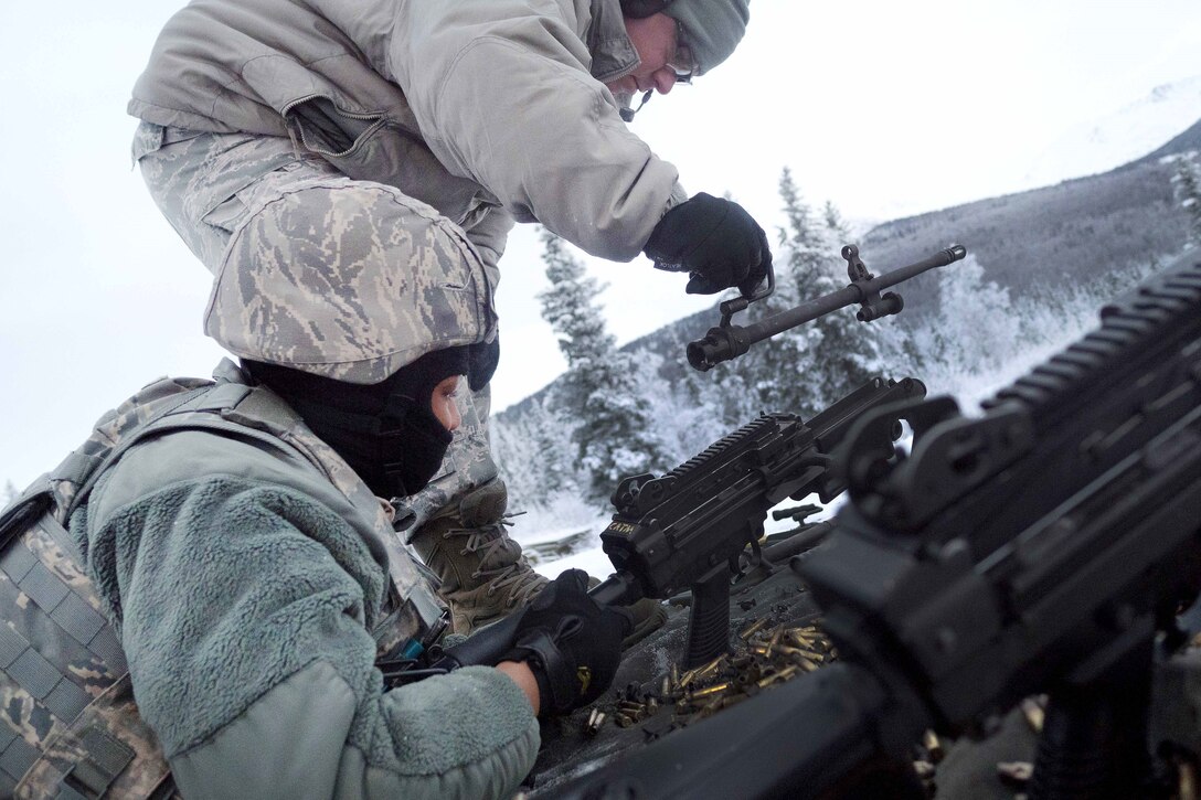 An Airman removes the barrel of an automatic weapon.