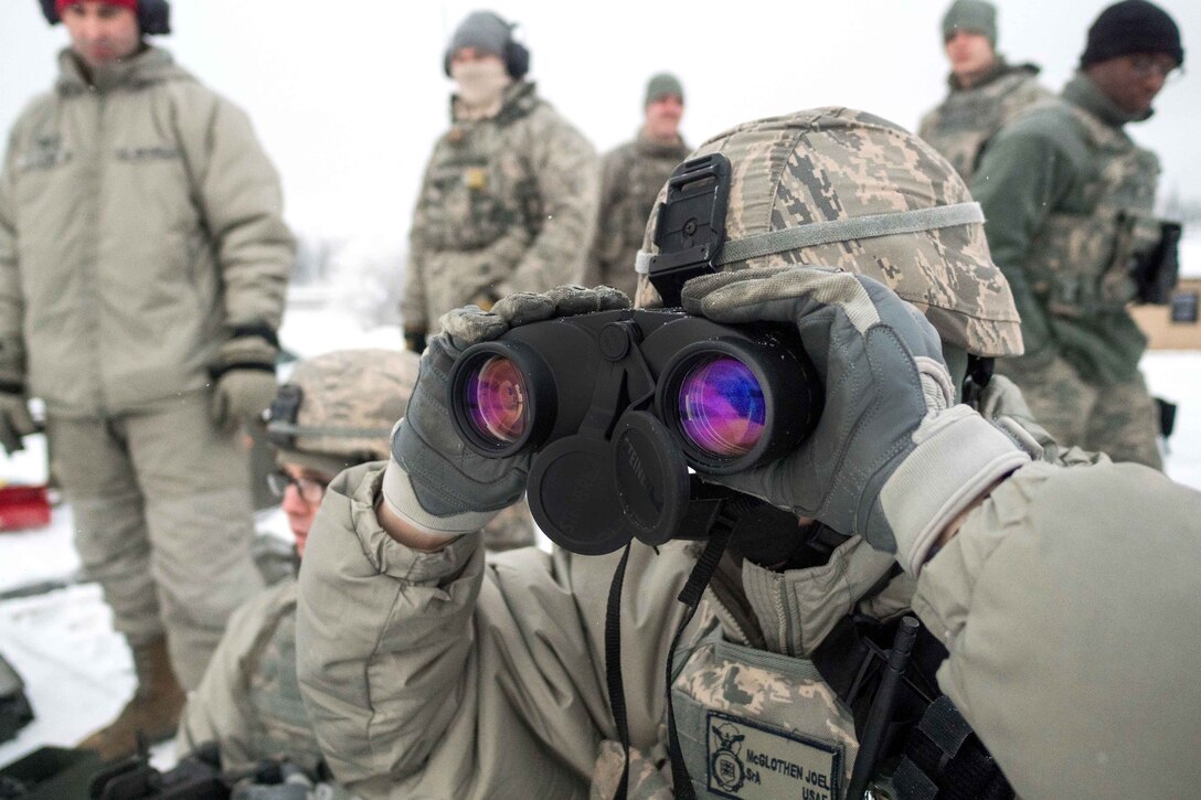 An airman uses binoculars to spot targets.