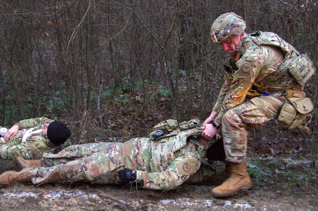 A soldier drags a person on the ground.