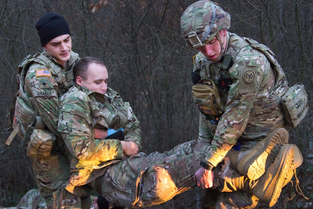 Two soldiers carry another soldier.