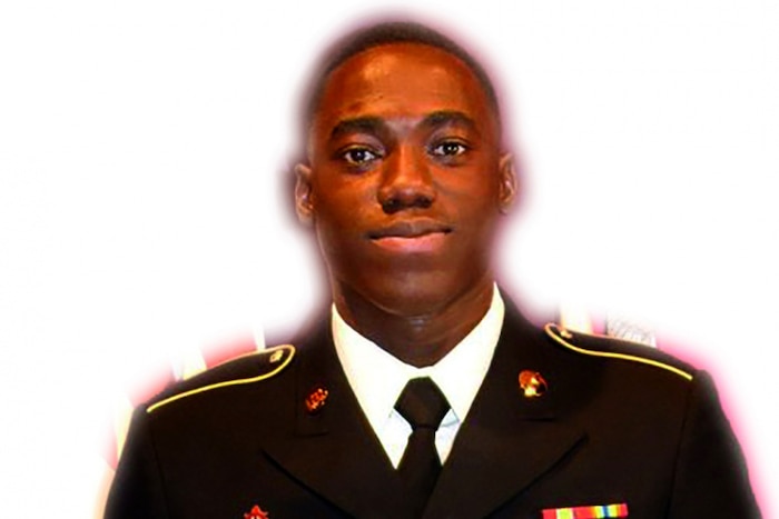 A soldier looks at the camera against a white background.