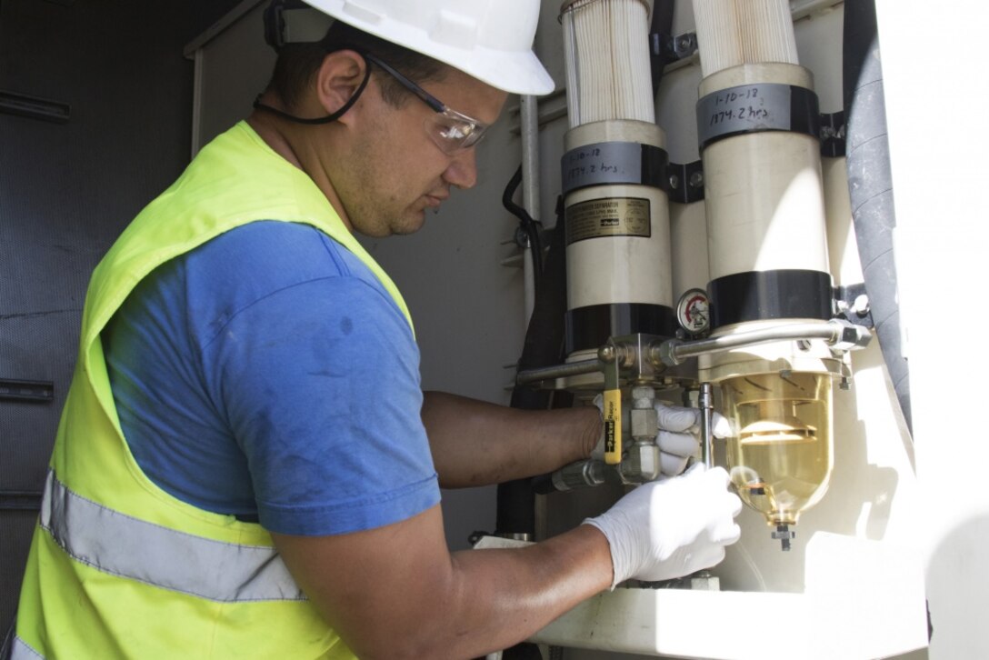 A contractor working with the Army Corps of Engineers in Puerto Rico ensures the fuel filter is working properly on a generator.