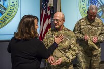 Lt. Col. Scott Grammer receives his new rank insignia from his wife, Stephanie Grammer, during his promotion ceremony to Colonel , January 11, 2017.