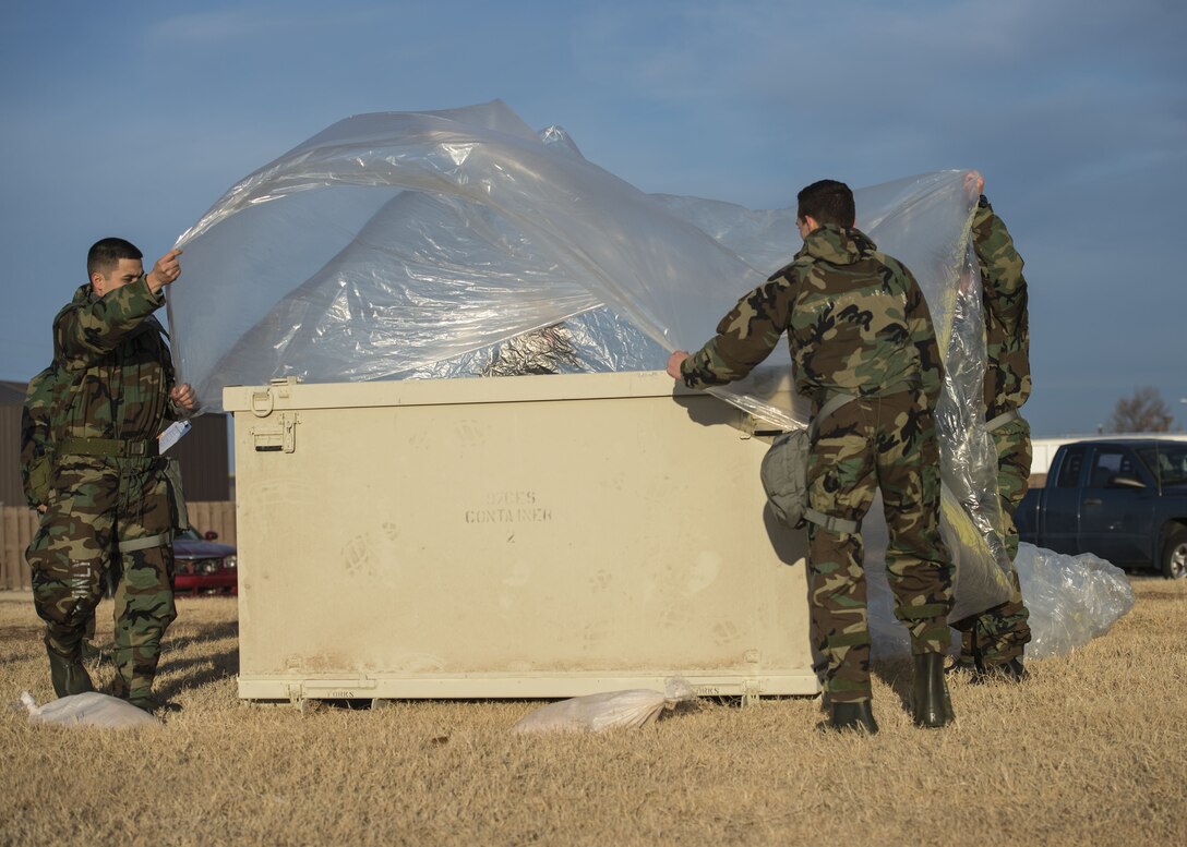 U.S. Air Force Airmen assigned to Altus Air Force Base, Okla., cover a storage unit with a tarp during an Ability to Survive and Operate (ATSO) exercise, Jan. 10, 2018, at Altus AFB.
