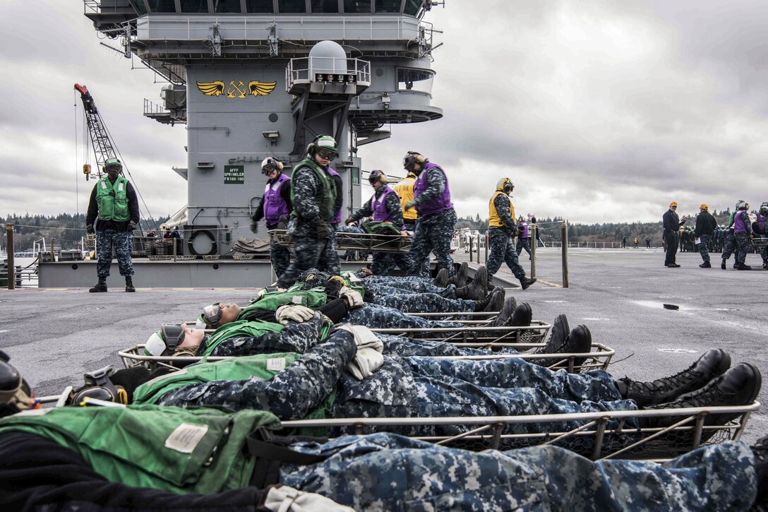 Sailors move simulated casualties during a firefighting and mass casualty drill