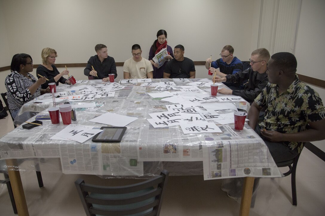 Students sit around a table practicing calligraphy