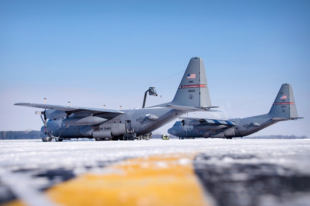 Guardsmen operate a deicing truck to remove ice and snow from the C-130H Hercules aircraft.