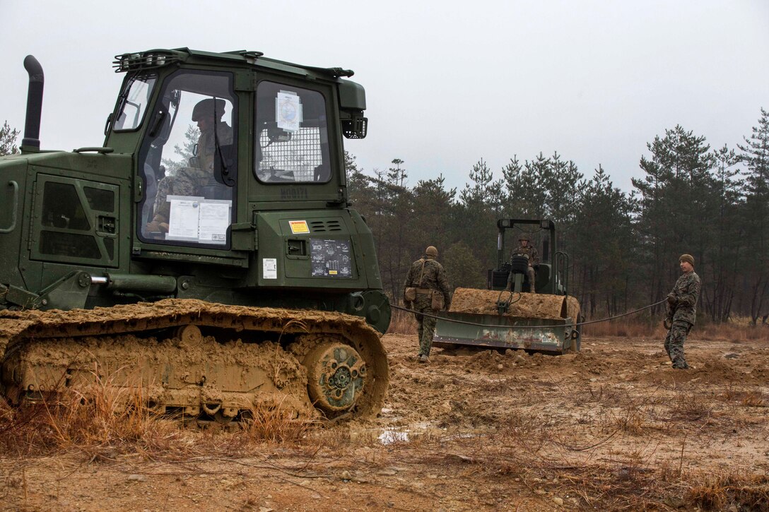 Marines operate heavy equipment to set up elements of a forward operating base.