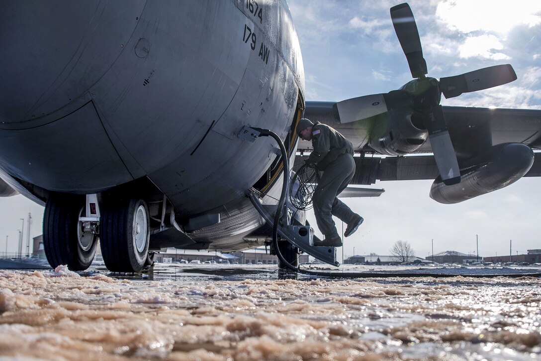 An airman inspects an aircraft surrounded in ice.