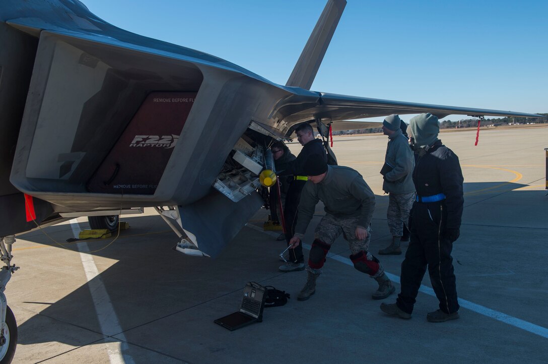 U.S. Air Force Airmen assigned to the 94th Aircraft Maintenance Unit load ammunition into a U.S. Air Force F-22 Raptor during the 4th Quarter Weapons Load Competition at Joint Base Langley-Eustis, Va., Jan. 2, 2018. To complete the competition, each load crew must successfully and correctly load one AIM-9X missile, one AIM-9M and one preloaded BRU-61 with four GBU-39 missiles into an F-22. (U.S. Air Force photo by Senior Airman Derek Seifert)