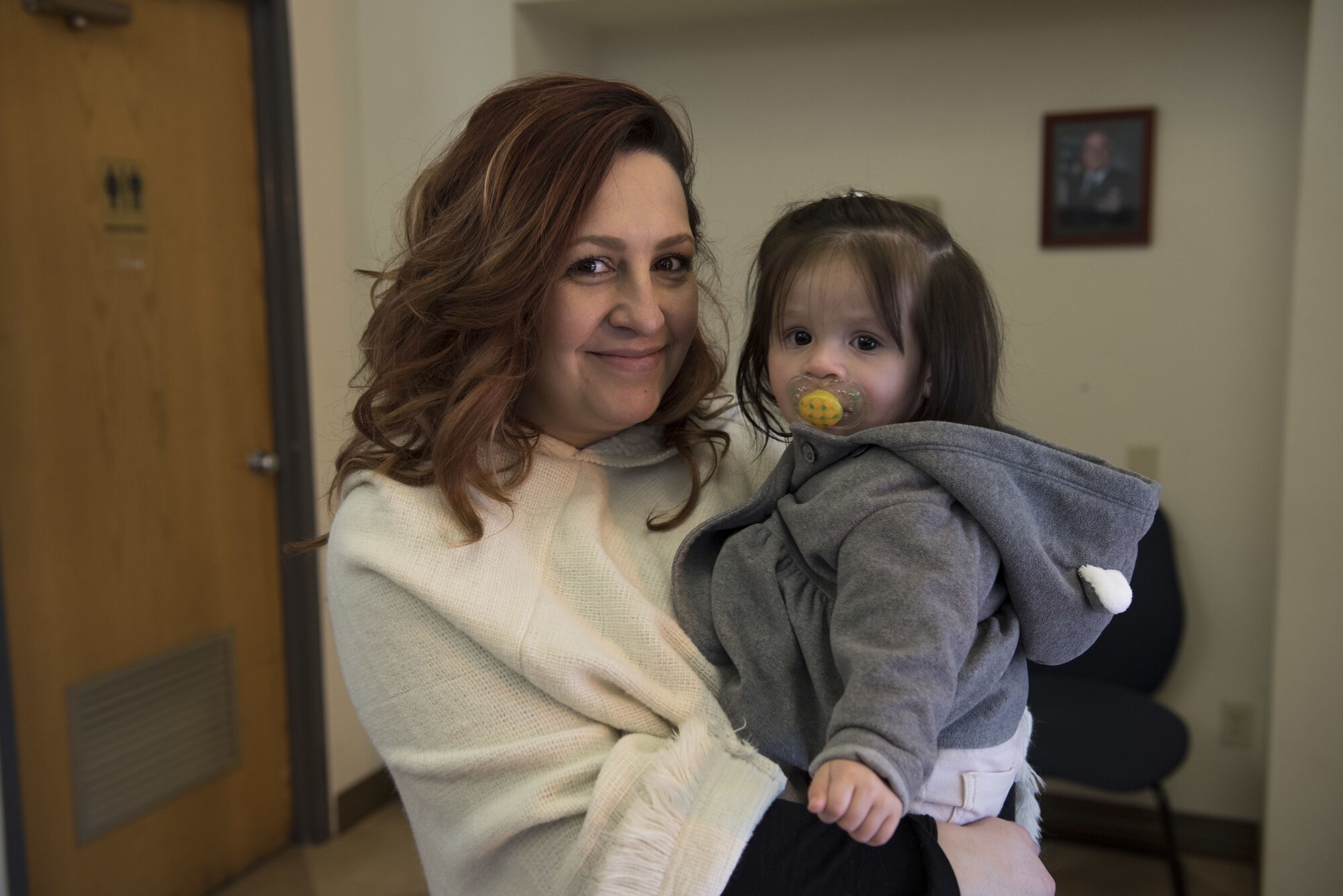 Rachel Trevino and her daughter Stella Trevino, pose for a photo at the Pass and Regristration Center Jan. 16, 2017, at Travis Air Force Base, Calif. The two came to Travis AFB in support for Rachel's mom, Karen Reed, who is a Gold Star family member who had just received a base pass. The Gold Star program first made an appearance during World War I after being placed over a service flag's blue star when a service member was killed in combat.