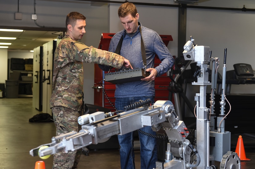 Senior Airman Matthew Koser, 628th Civil Engineer Squadron explosive ordnance disposal flight technician, shows Joey Leech, South Carolina Stingrays defensemen, how to operate the EOD robot at the EOD building, Jan. 10, 2018.