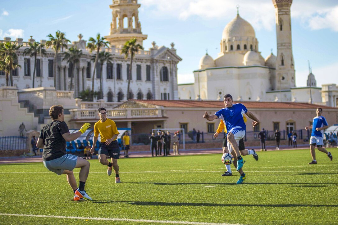 Sailors play soccer on a field.