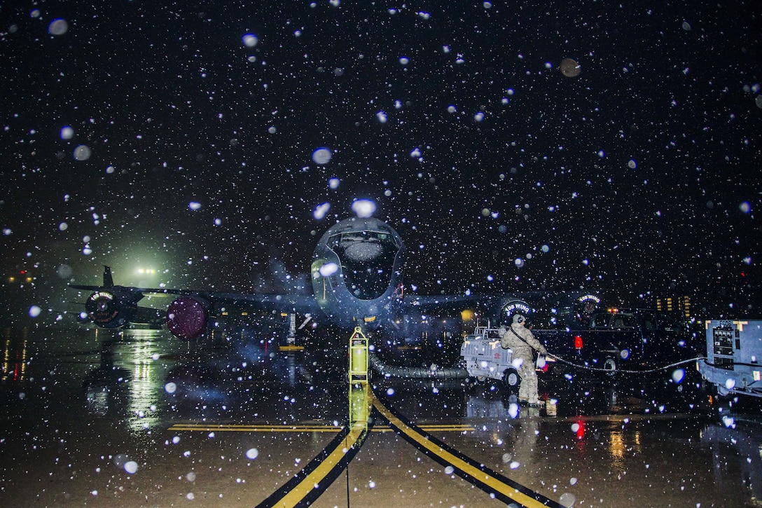 Guardsmen prepare to refuel a KC-135 Stratotanker before a flight during a snow shower.