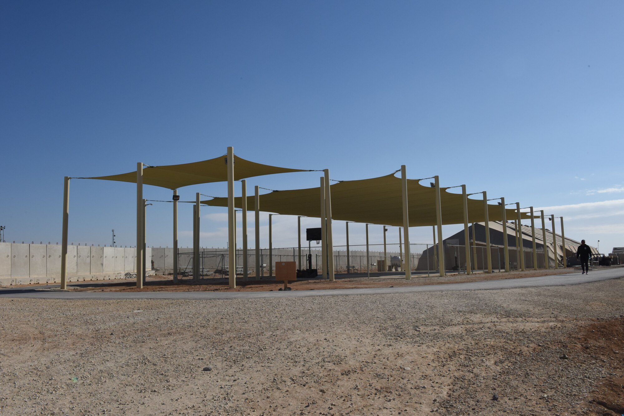 An Airman walks around the track near the recently constructed sunshade outside the Legends Fitness Center at the 332nd Air Expeditionary Wing Jan 18, 2018. The completed construction project is the largest sunshade in the area of responsibility. (U.S. Air Force photo by Staff Sgt. Antonio Gonzalez/Released)