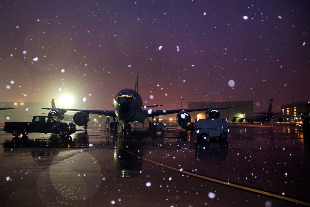 Guardsmen perform final inspection checks on a KC-135 Stratotanker before a flight during a snow shower.