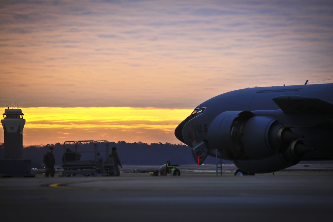 Guardsmen perform maintenance on a KC-135 Stratotanker at sunrise.