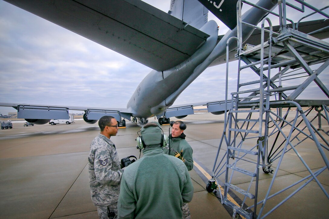Staff Sgt. Garion Reddick, left, talks with Tech. Sgt. Raymond DeMarco, center, and Staff Sgt. Robert Cento about a lighting issue on a KC-135 Stratotanker.