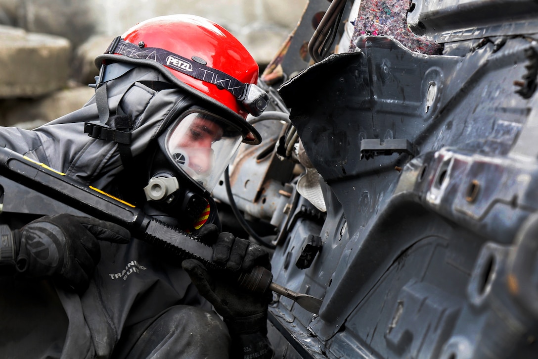 Army Reserve Spc. Jeffrey Evans uses a powered device to search a damaged vehicle for possible victims.