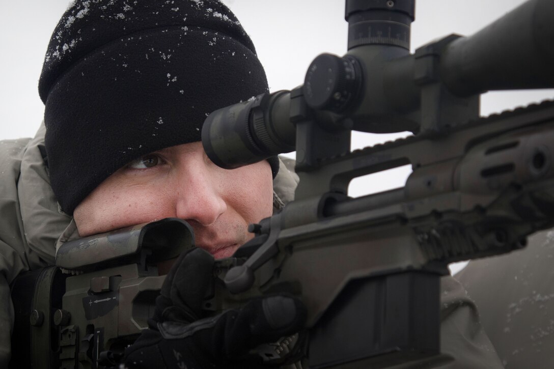 A soldier peers through the scope on an M2010 rifle.