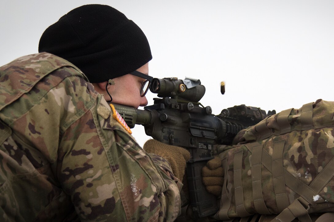 A soldier fires an M4 rifle at targets at a range.