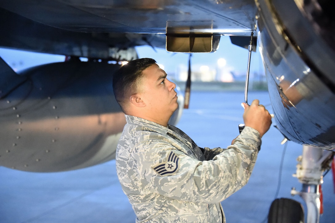 An airman performs pre-flight checks on an F-15C Eagle fighter aircraft.