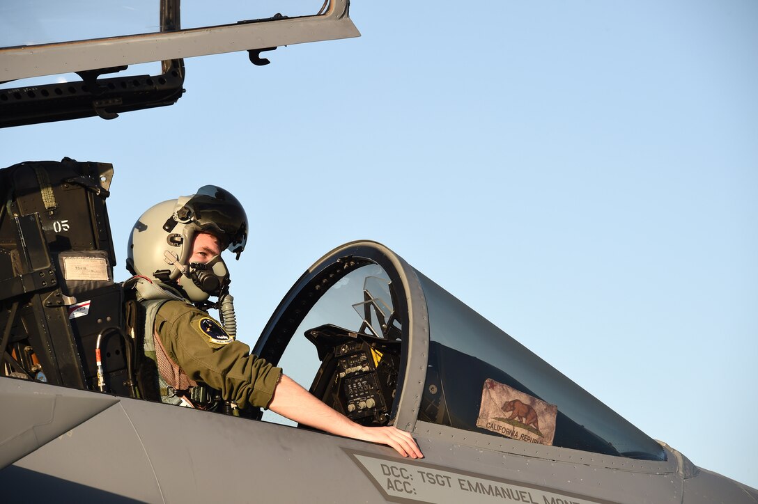 An airmen sitting in a cockpit waits for the signal to fire up the engines of his F-15C Eagle fighter aircraft.