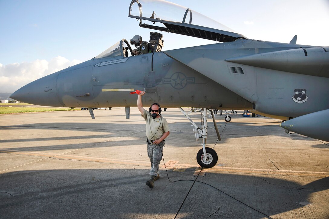An airman pulls the front landing gear pin on the F-15C Eagle fighter aircraft.