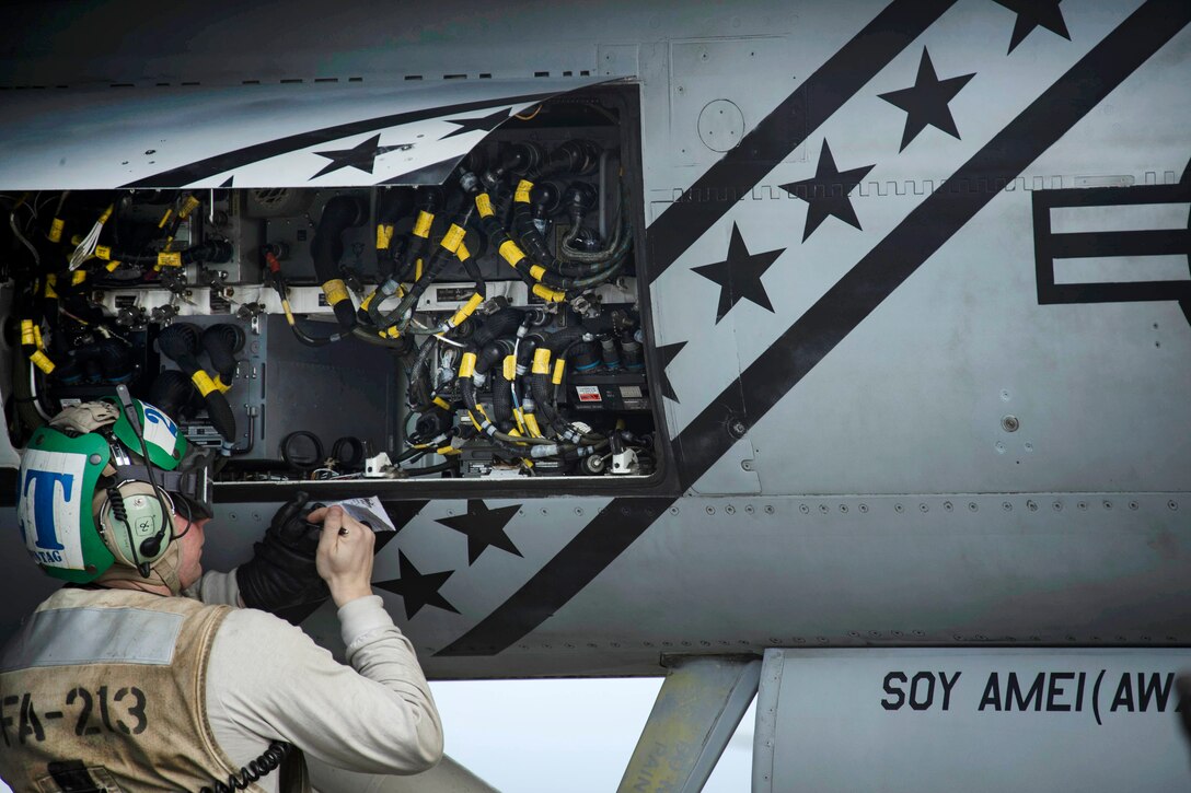 A sailor performs maintenance on the avionics equipment of an F/A18F Super Hornet.