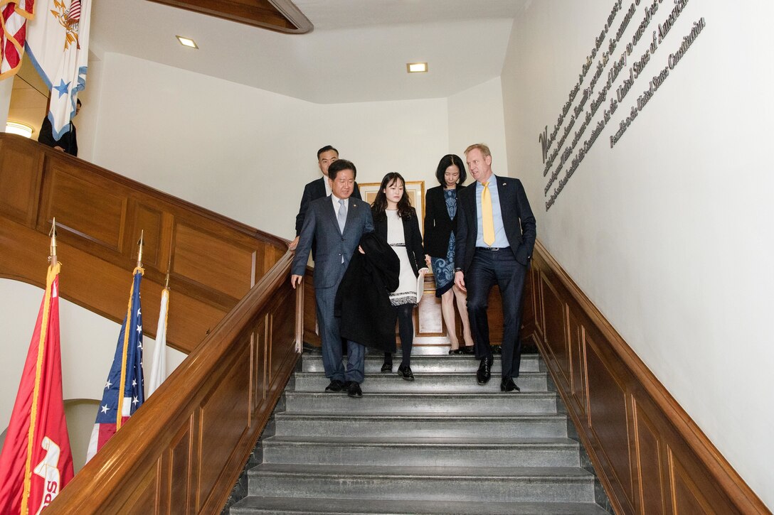 The deputy defense secretary walks down a staircase with a group of people.
